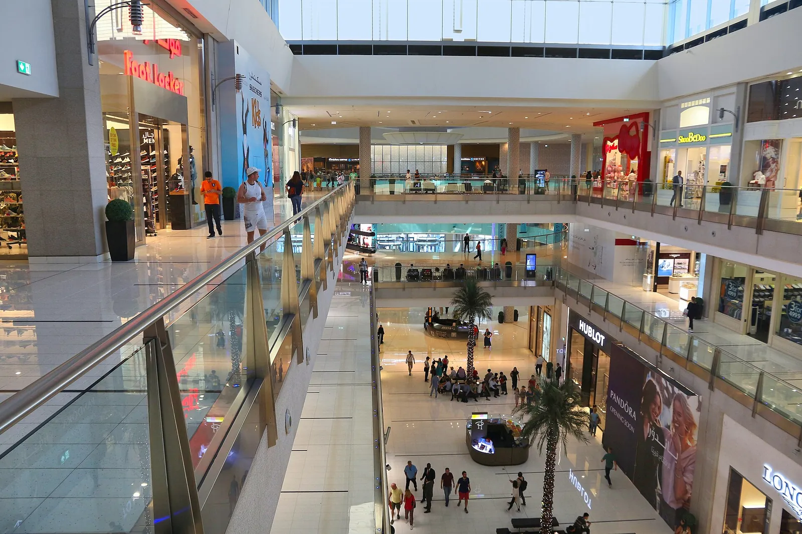 Bright multi-level atrium of The Dubai Mall with palm trees and shopfronts